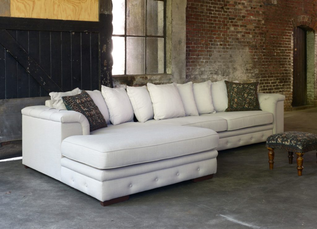 Canapé d'angle Julia avec détails capitonnés de couleur beige clair.