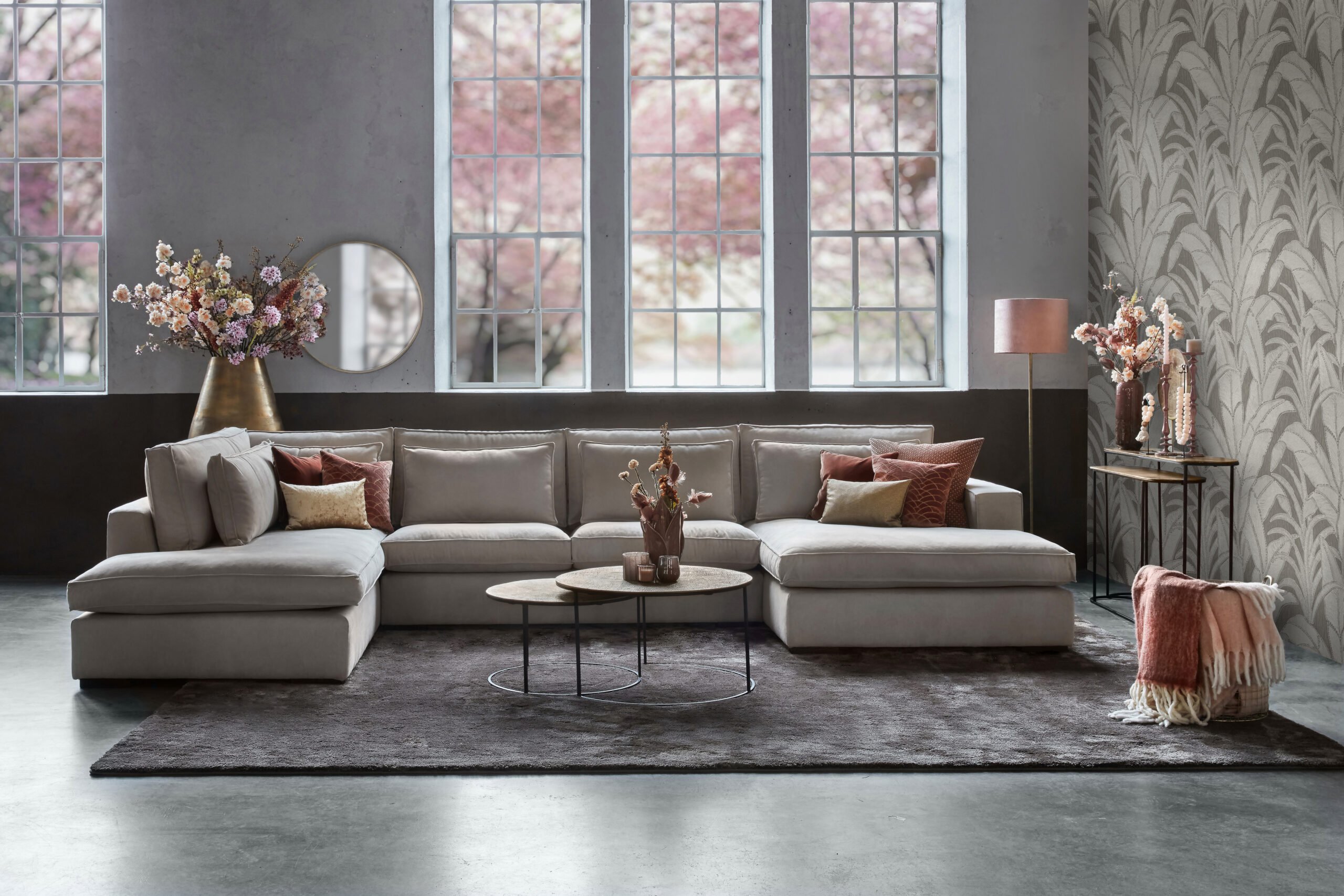 Helles Ecksofa Annabelle Square mit runden Couchtischen und großem Teppich.