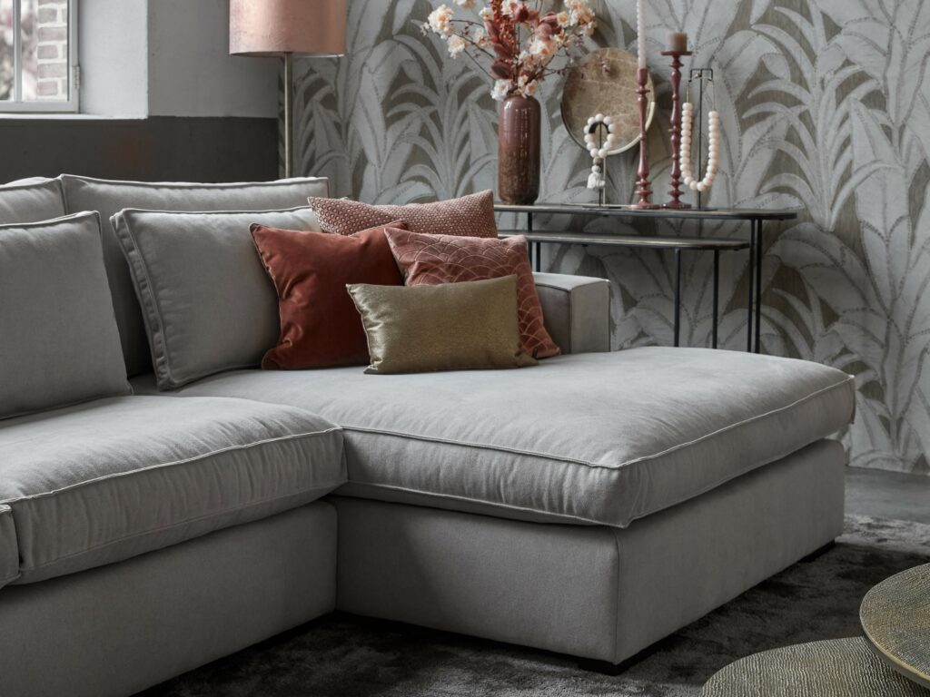 Helles Ecksofa Annabelle Square mit runden Couchtischen, rosa Dekoration und einem großen Teppich.