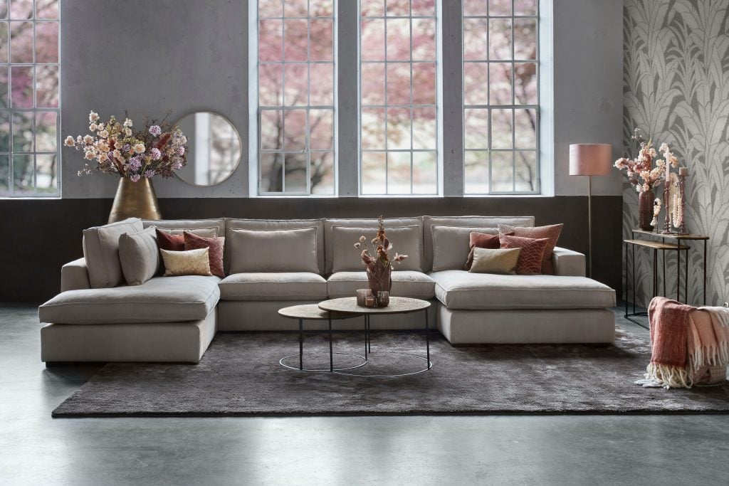 Helles Ecksofa mit rosa Accessoires