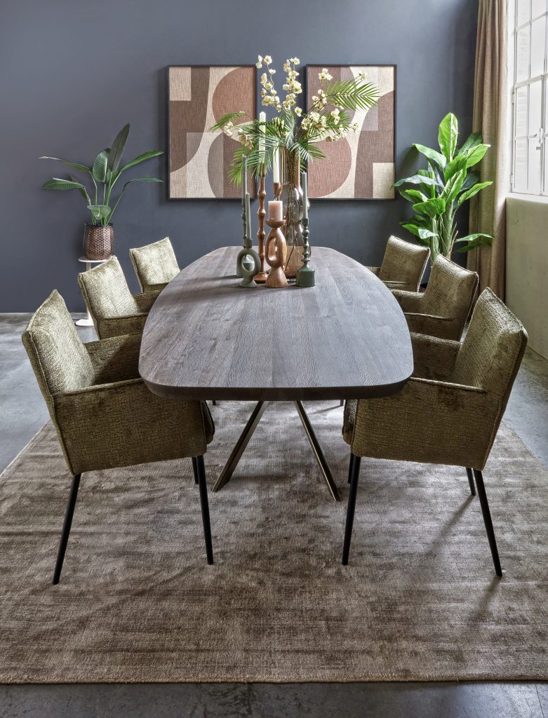 Deens ovale eettafel in een donkere bruine kleur. Massief hout. Met mos groene eetkamerstoelen met armleuning. Sfeervolle afstyling.