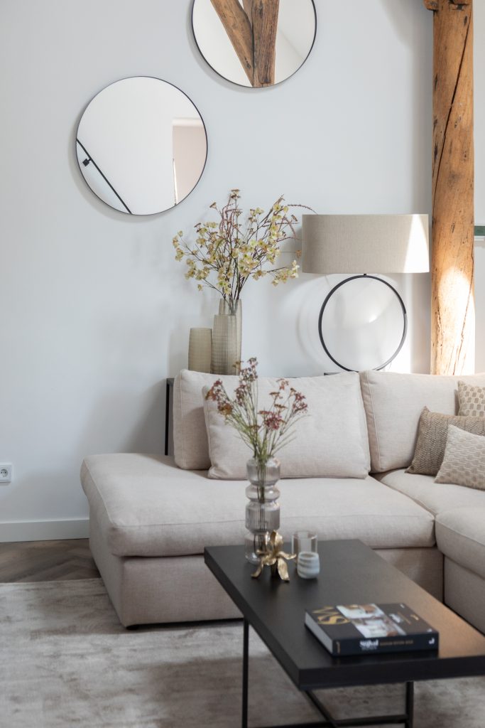 Round mirrors in the living room above a bright sofa.