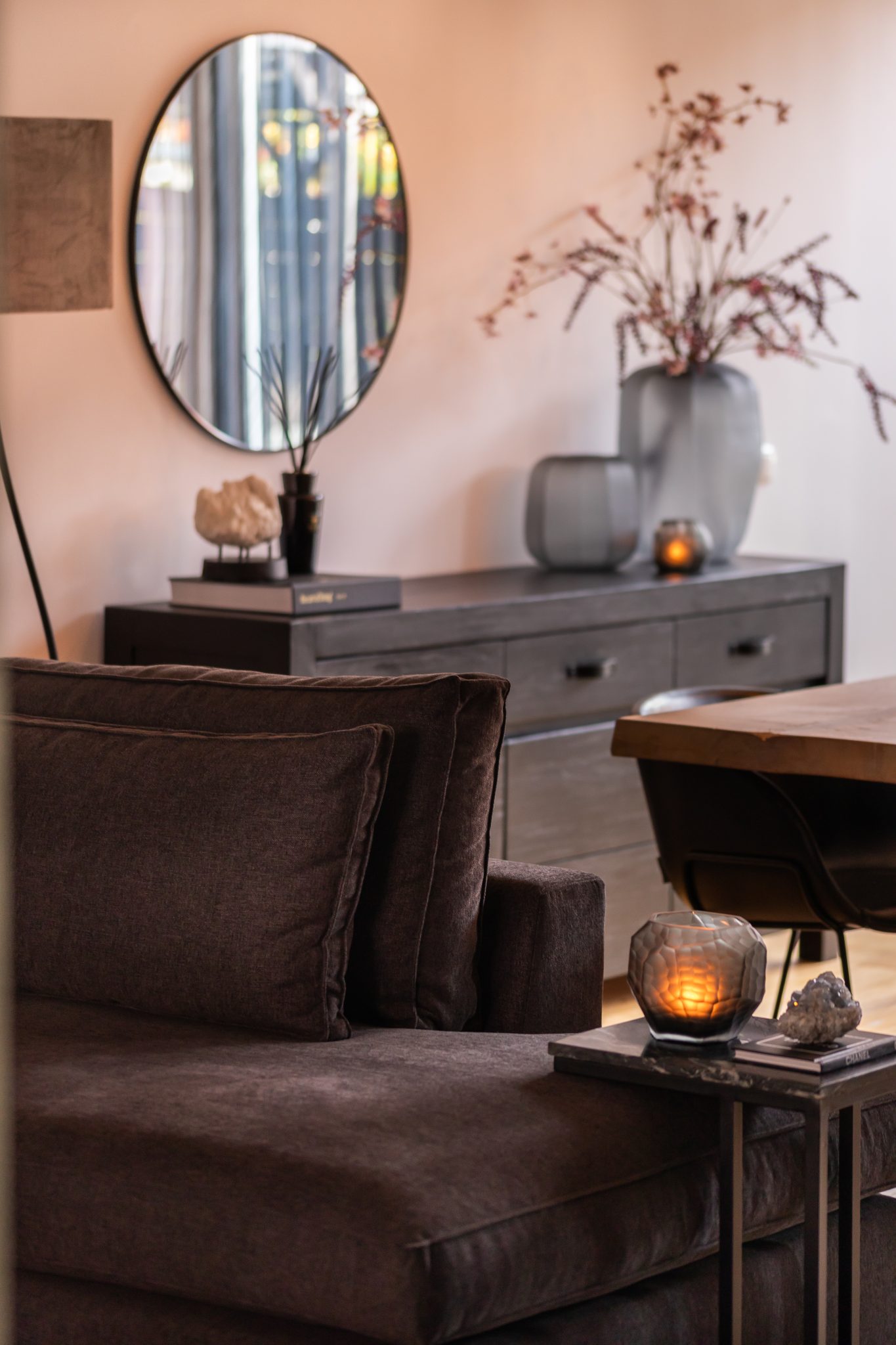 Stijlvol interieur met ronde spiegel en groter vazen met takken erin,.