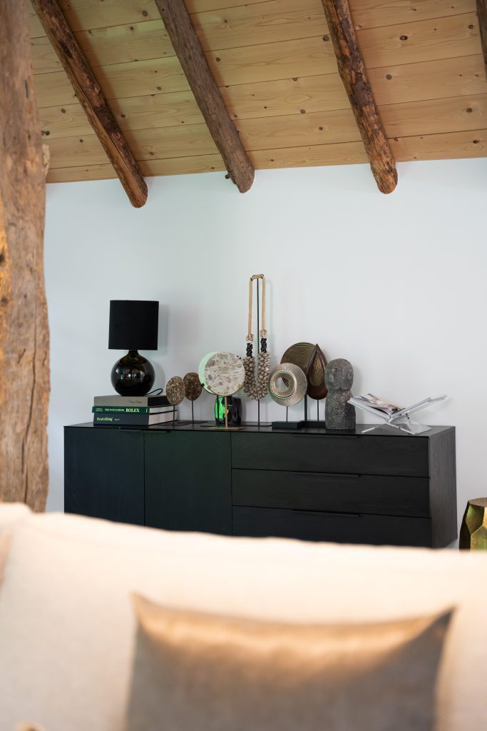 Accessories on a matte black dresser with round shapes.