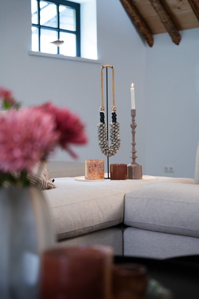 Grote hoekbank in u-opstelling met een donker kleed en chique accessoires.