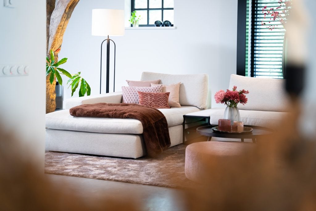 Grote hoekbank in u-opstelling met een donker kleed en chique accessoires.