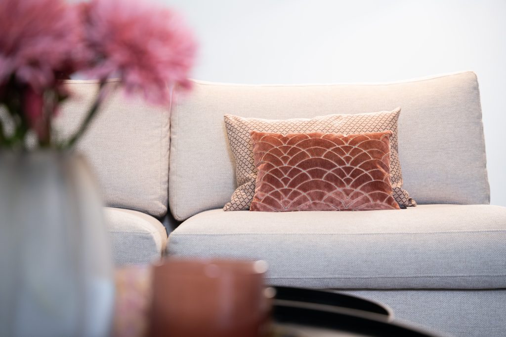 Grote hoekbank in u-opstelling met een donker kleed en chique accessoires.