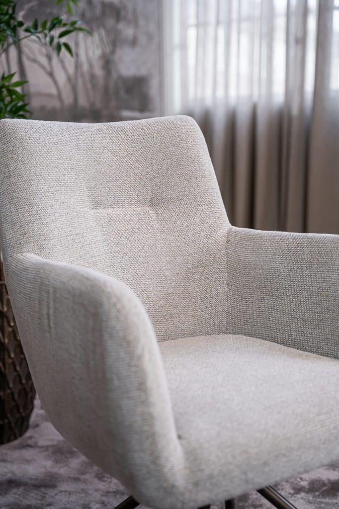 Detail van lichte natural eetkamerstoel met armleuning.