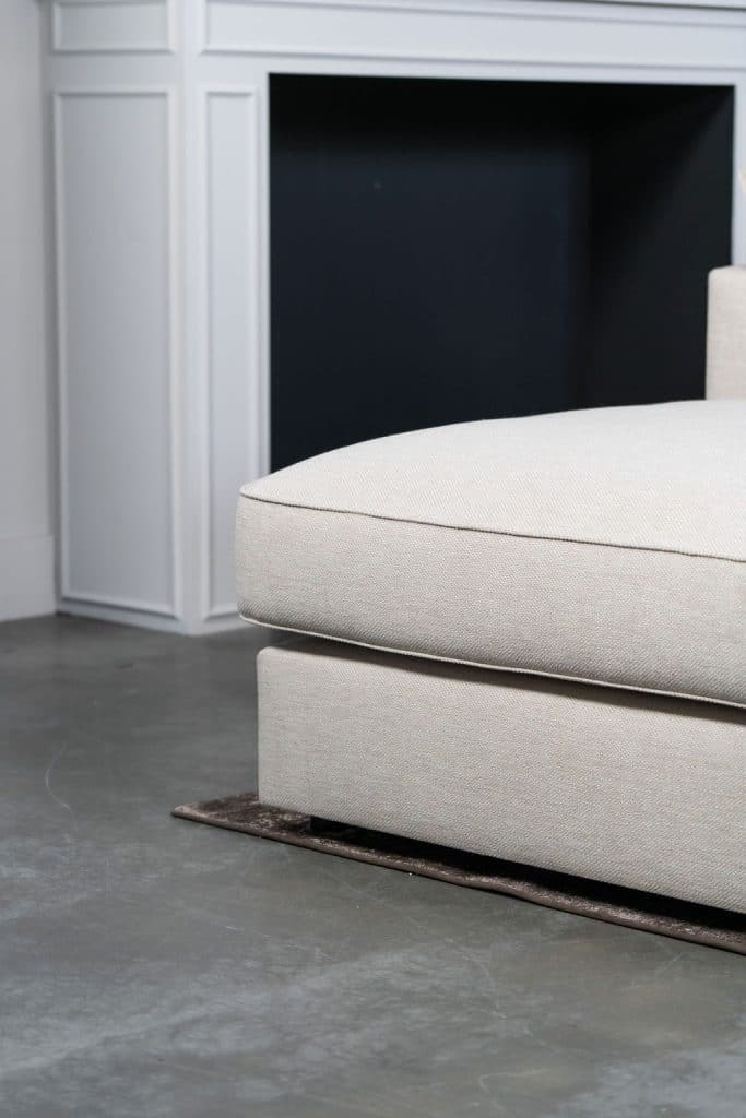 Béžová rohová sedací souprava s velkým rohem, stylizovaná s bytovými doplňky v Burgundsku.