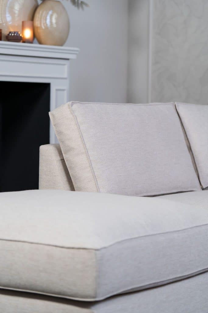 Béžová rohová sedací souprava s velkým rohem, stylizovaná s bytovými doplňky v Burgundsku.