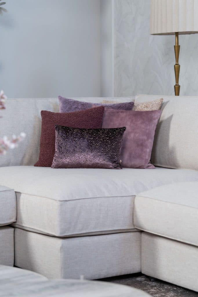 Béžová rohová sedací souprava s velkým rohem, stylizovaná s bytovými doplňky v Burgundsku.