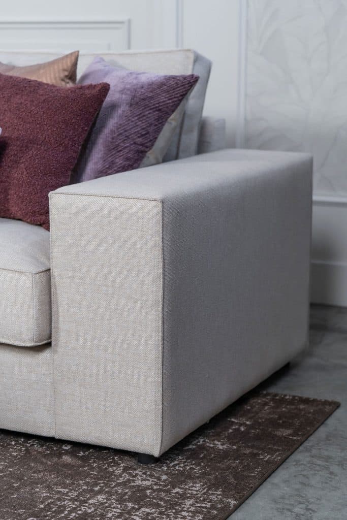 Béžová rohová sedací souprava s velkým rohem, stylizovaná s bytovými doplňky v Burgundsku.