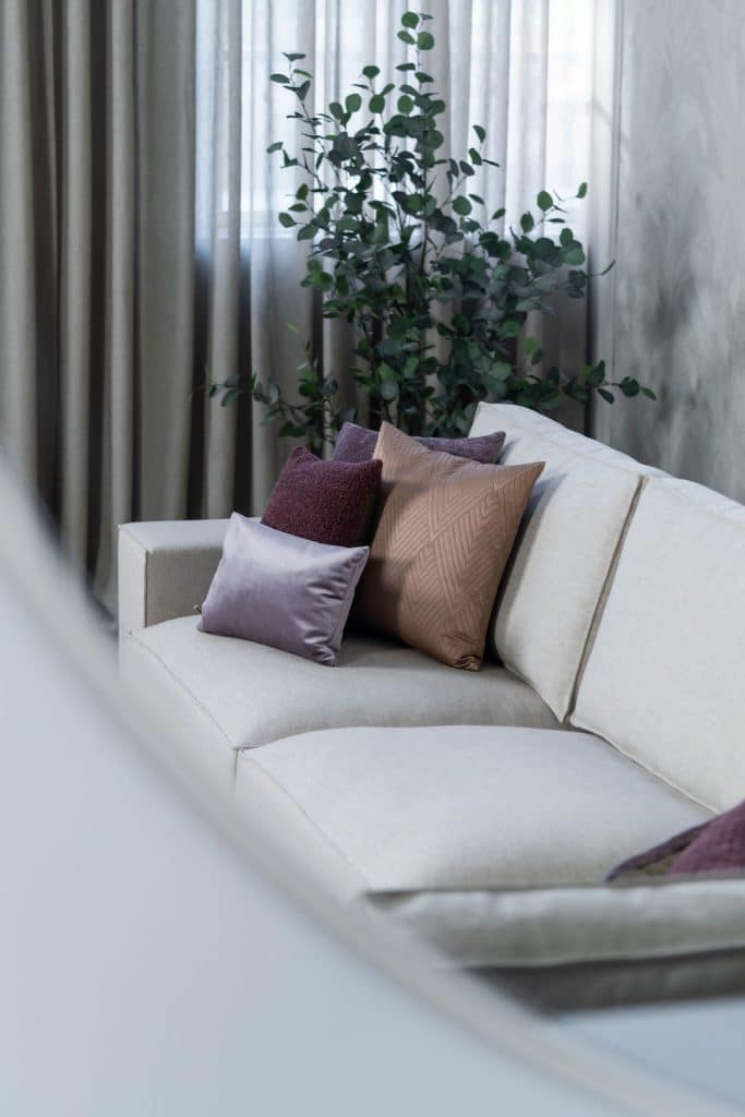 Béžová rohová sedací souprava s velkým rohem, stylizovaná s bytovými doplňky v Burgundsku.