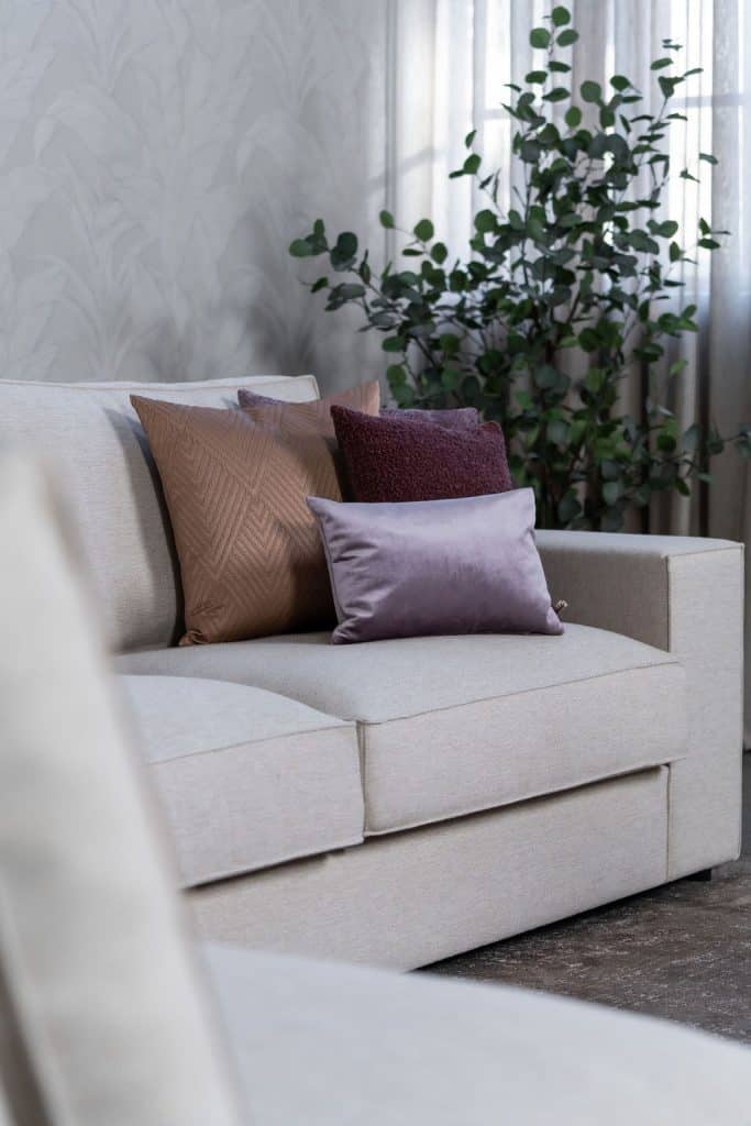 Béžová rohová sedací souprava s velkým rohem, stylizovaná s bytovými doplňky v Burgundsku.