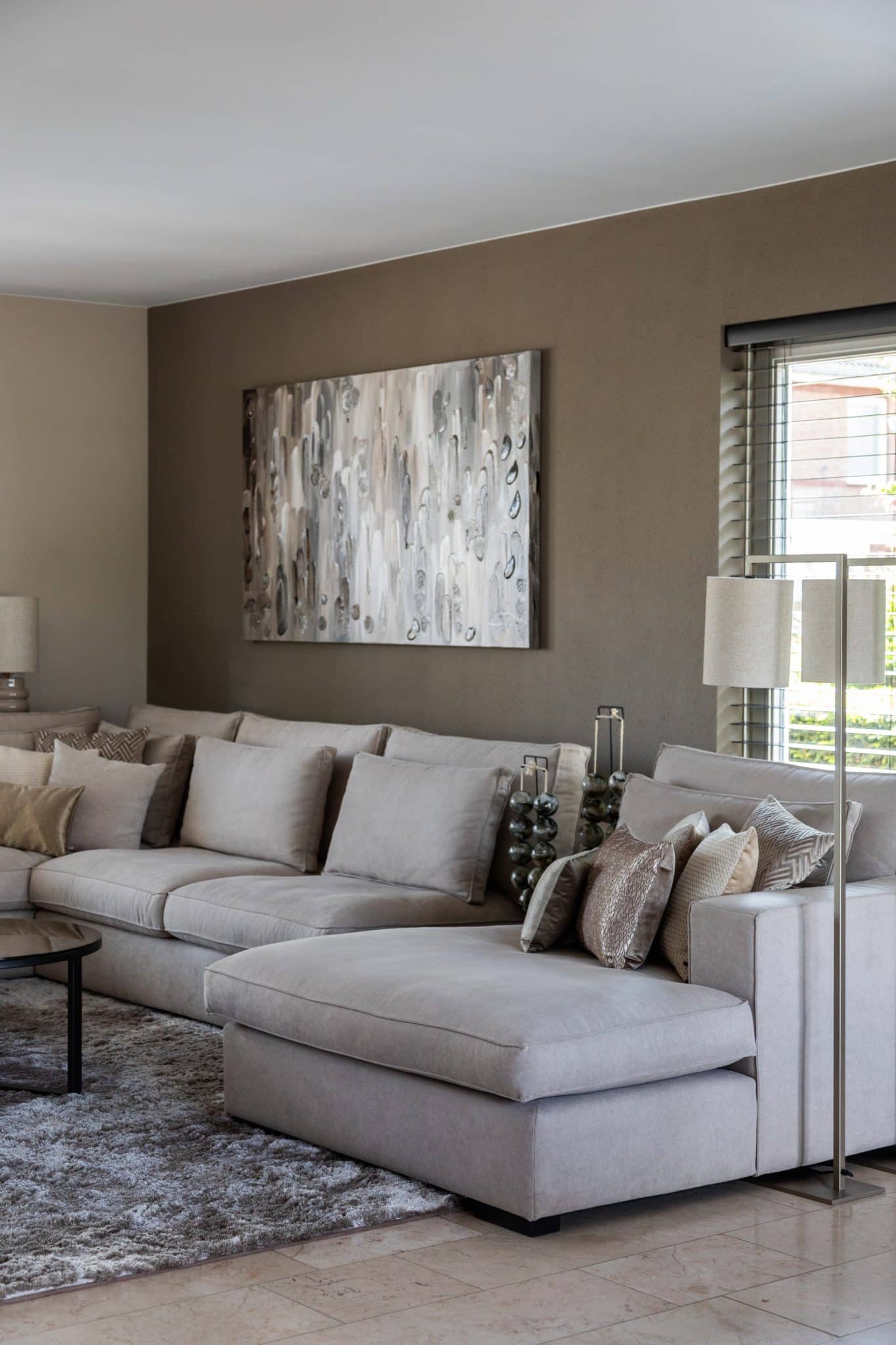 Binnenkijken bij klanten thuis met een grote beige lounge bank en chique eettafel met bijpassende eetkamerstoelen.