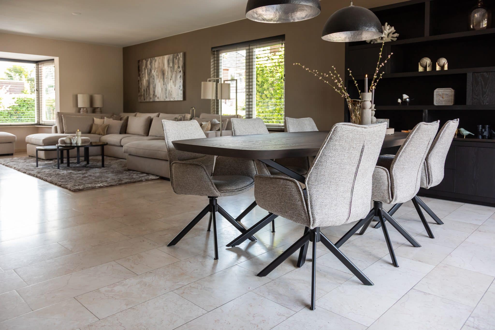 Binnenkijken bij klanten thuis met een grote beige lounge bank en chique eettafel met bijpassende eetkamerstoelen.