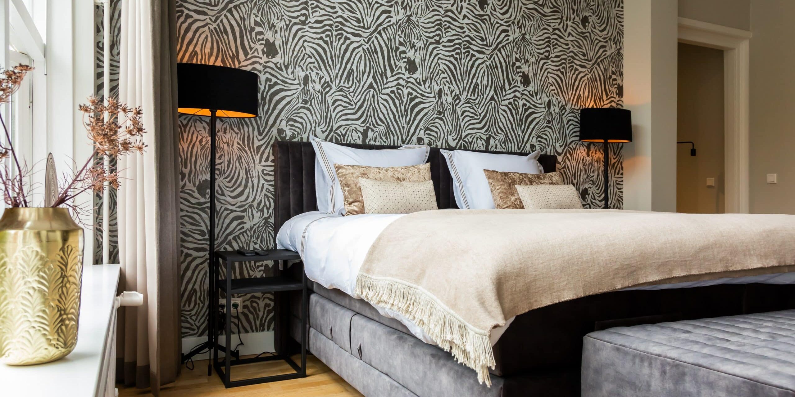 Dark gray bed with zebra print wallpaper and a carpet